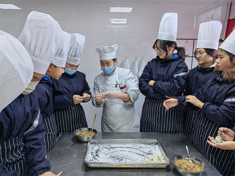 圖片1：學生們認真向餐廳師傅學習包餃子.jpg